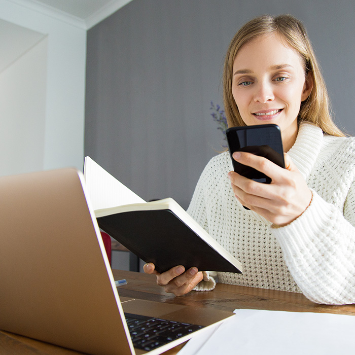 Smiling pretty lady checking timetable while texting sms